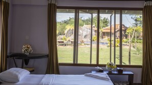 A hotel room with two beds, a desk with a vase of flowers, a view of a pool and outdoor area.