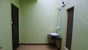 A bathroom with a green wall, a white sink, a mirror, and a door. - Steung Chinet Bungalow (Santuk)