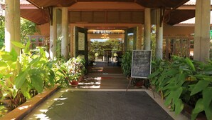 A covered walkway with potted plants on either side, leading to a building entrance. - Steung Chinet Bungalow (Santuk)
