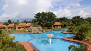 A swimming pool with a unique design, surrounded by lounge chairs and a tropical garden.