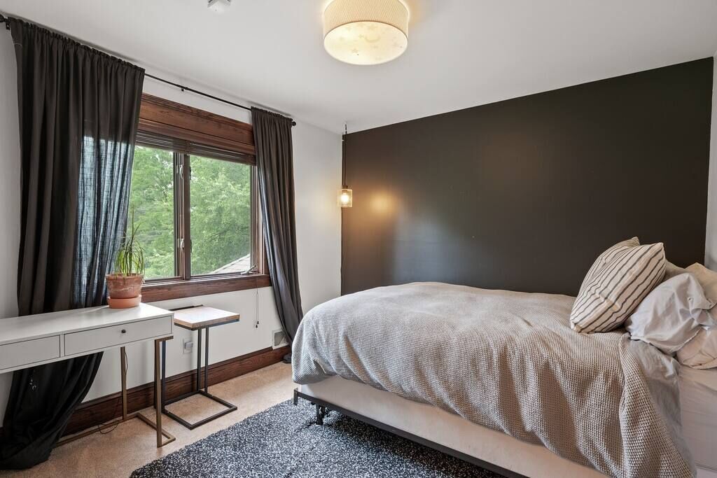 Ein Schlafzimmer mit einem Bett, einem Schreibtisch und einem Fenster mit Vorhängen.