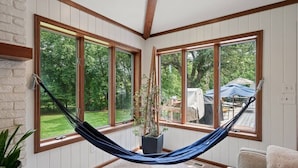 Ein Zimmer mit großen Fenstern, einer Hängematte und einem Blumentopf.