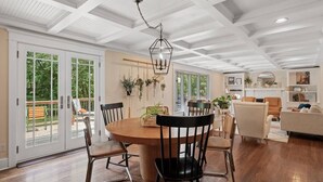 Ein geräumiges Wohnzimmer mit einem Holzesstisch, schwarzen Stühlen und einer Hängeleuchte.