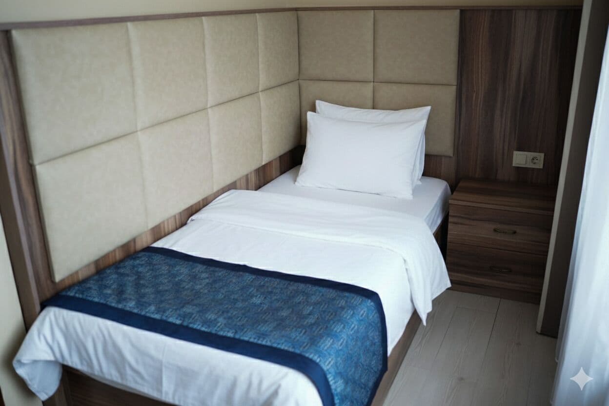 A single bed with a headboard, a bedside table, and a blue blanket.