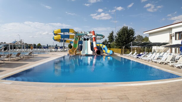 Una piscina con tobogán y sillas de descanso.