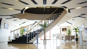 Un moderno vestíbulo de hotel con una escalera espiral, suelos pulidos y un mostrador de recepción.
