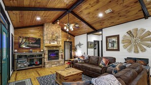 A rustic interior with a stone fireplace, leather furniture, and wooden beams. - Holly Hill Secluded Retreat 7 acrs, Perfect 2 Bedroom, Hot Tub, Pets (Broken Bow)