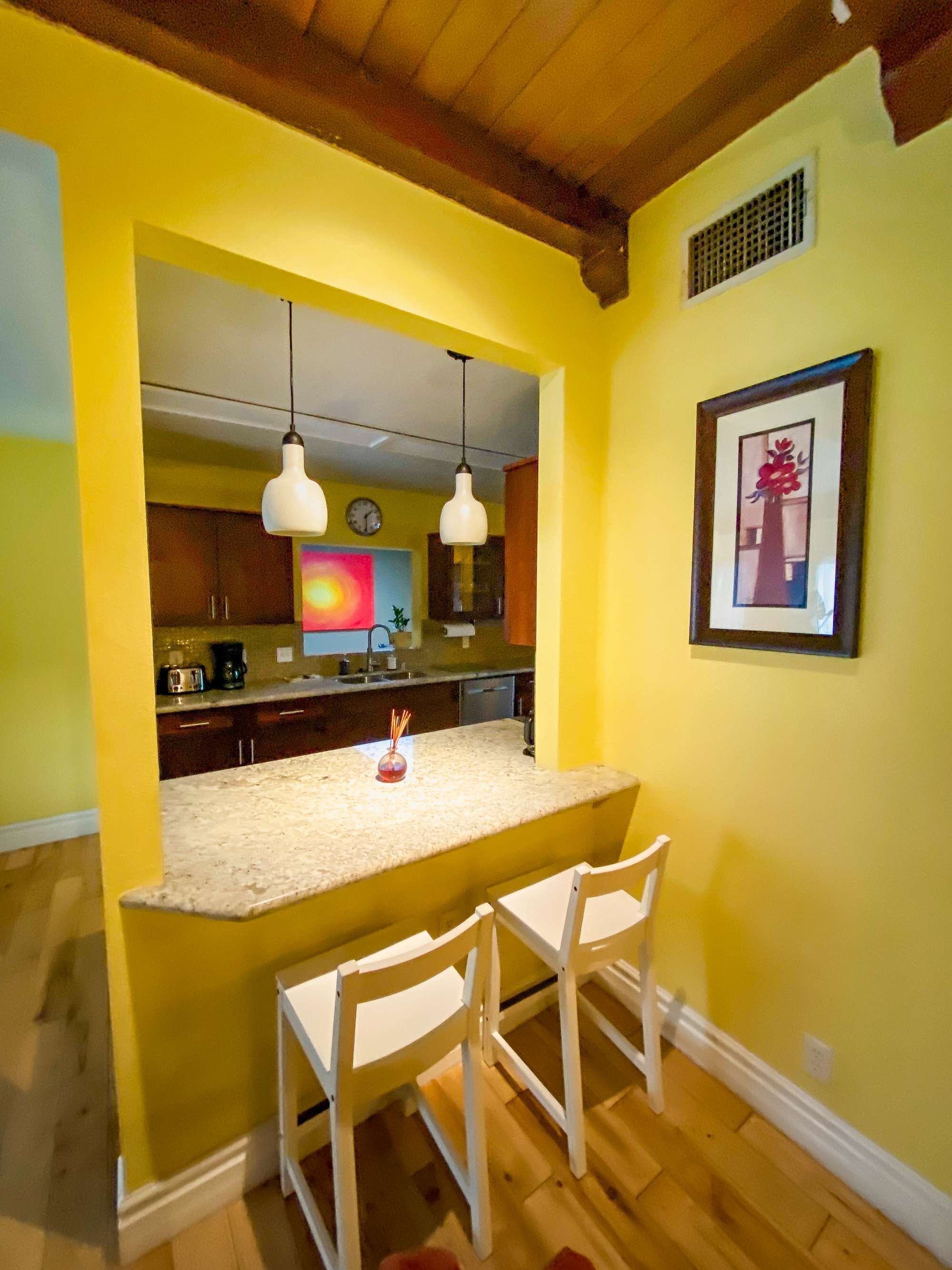 A kitchen with a central island, two pendant lights, and a framed picture on the wall.