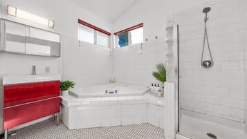 Une salle de bain moderne avec une douche carrelée de carreaux blancs, un meuble-lavabo rouge et un grand miroir.