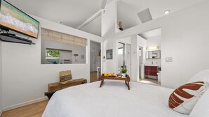 Une chambre moderne avec un grand lit, un banc en bois et un plateau contenant des éléments pour le petit-déjeuner.