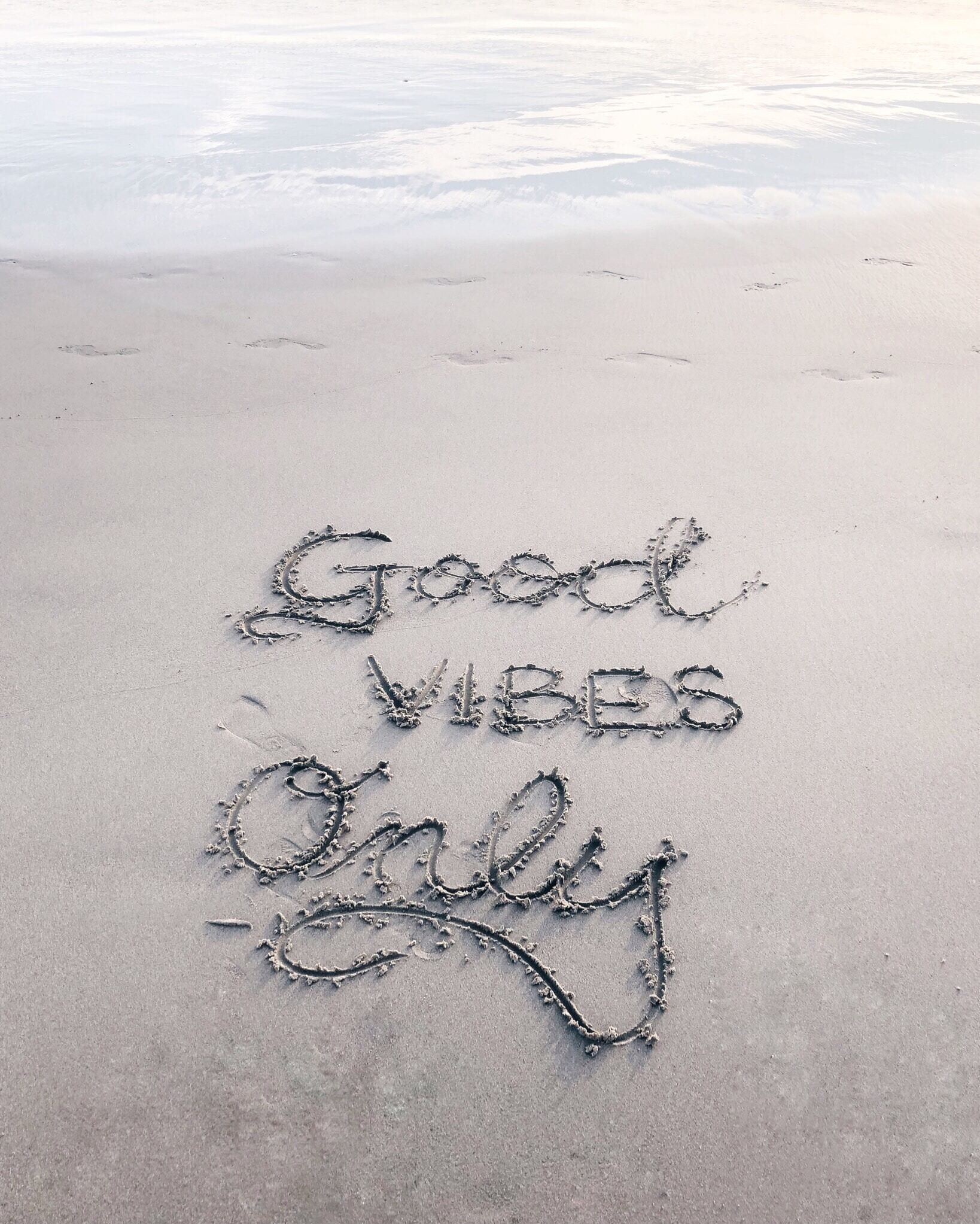 A beach with the words "Good Vibes Only" written in the sand.