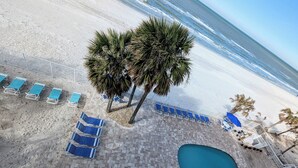 Ein Poolbereich am Strand mit Liegestühlen, einem Schwimmbecken und Palmen.