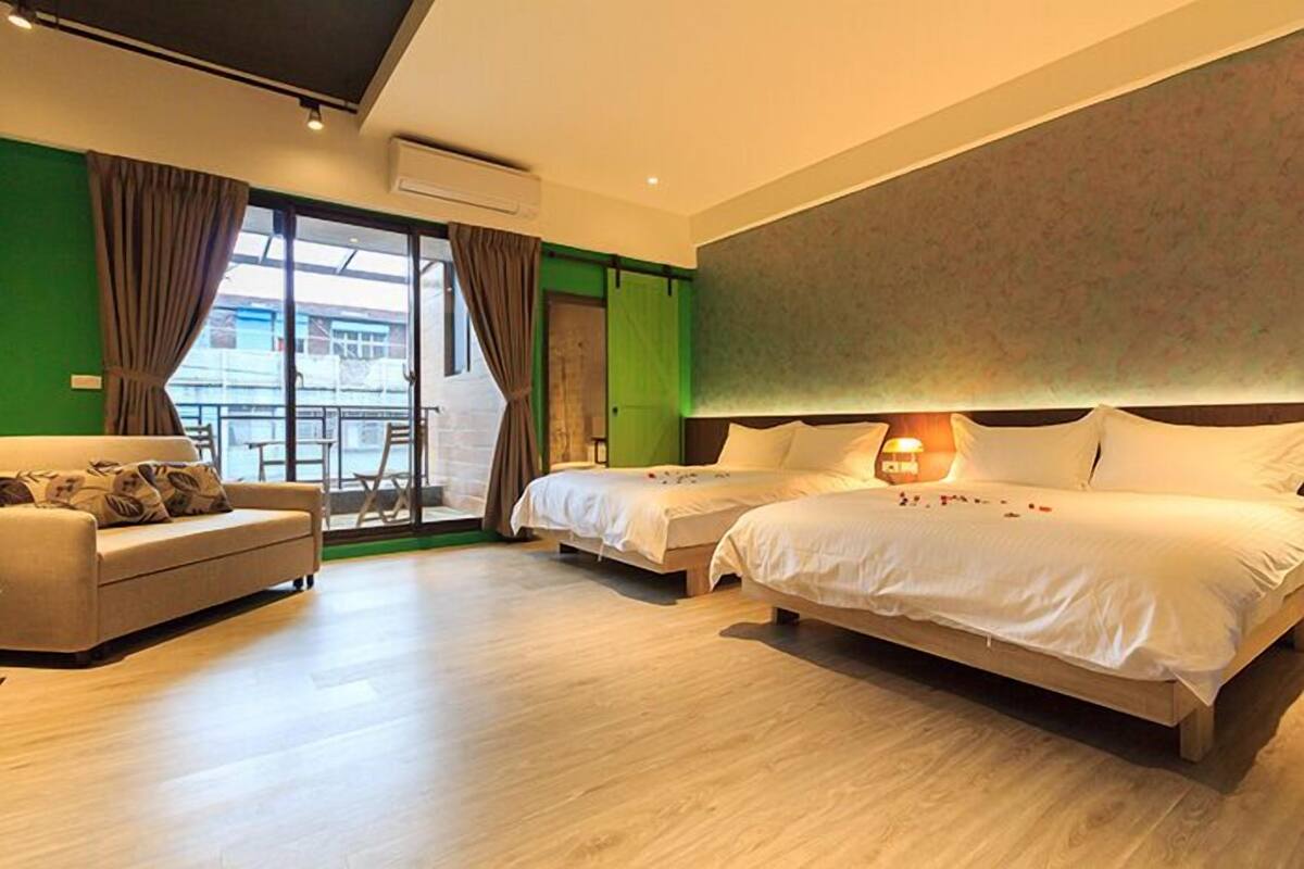 Una habitación de hotel moderna con dos camas, un sofá y un amplio ventanal.