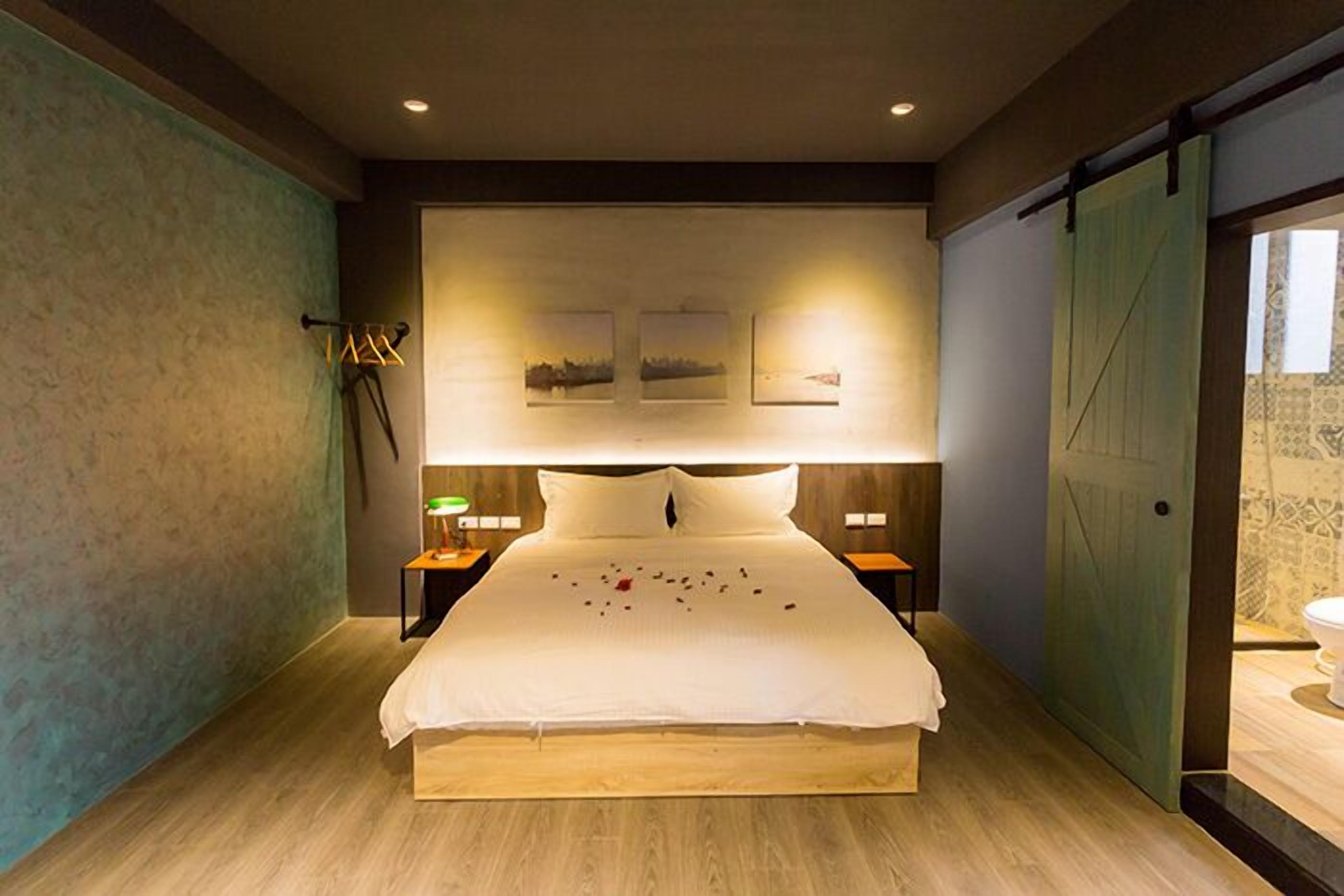 A modern bedroom with a large bed, two bedside tables with lamps, and three framed pictures on the wall.
