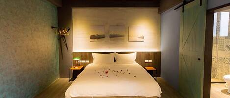 A modern bedroom with a large bed, two bedside tables with lamps, and three framed pictures on the wall.