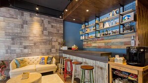 Un espace bar moderne avec un canapé, des tabourets et une machine à café.