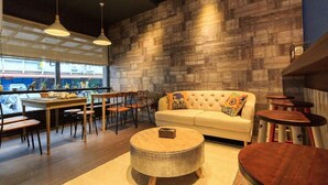 Un intérieur moderne avec un mur en bois, un canapé blanc, une table basse ronde et un coin repas comprenant des chaises et une table.