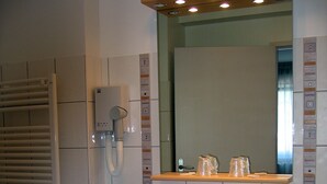 Een badkamer met een wastafel, spiegel, handdoekhouder en een telefoon aan de muur.