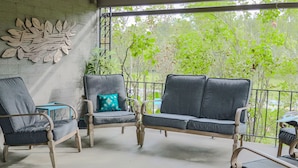 A covered outdoor seating area with wicker furniture and a decorative wall.
