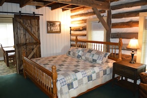 Ein rustikales Schlafzimmer mit einem hölzernen Bett, einem Nachttisch mit Lampe und einem Sessel.