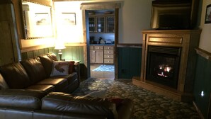 Una sala de estar con un sofá de cuero, una chimenea y una zona de cocina al fondo.