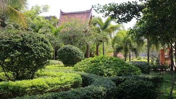 A traditional building with a tiled roof, surrounded by well-maintained greenery and palm trees.