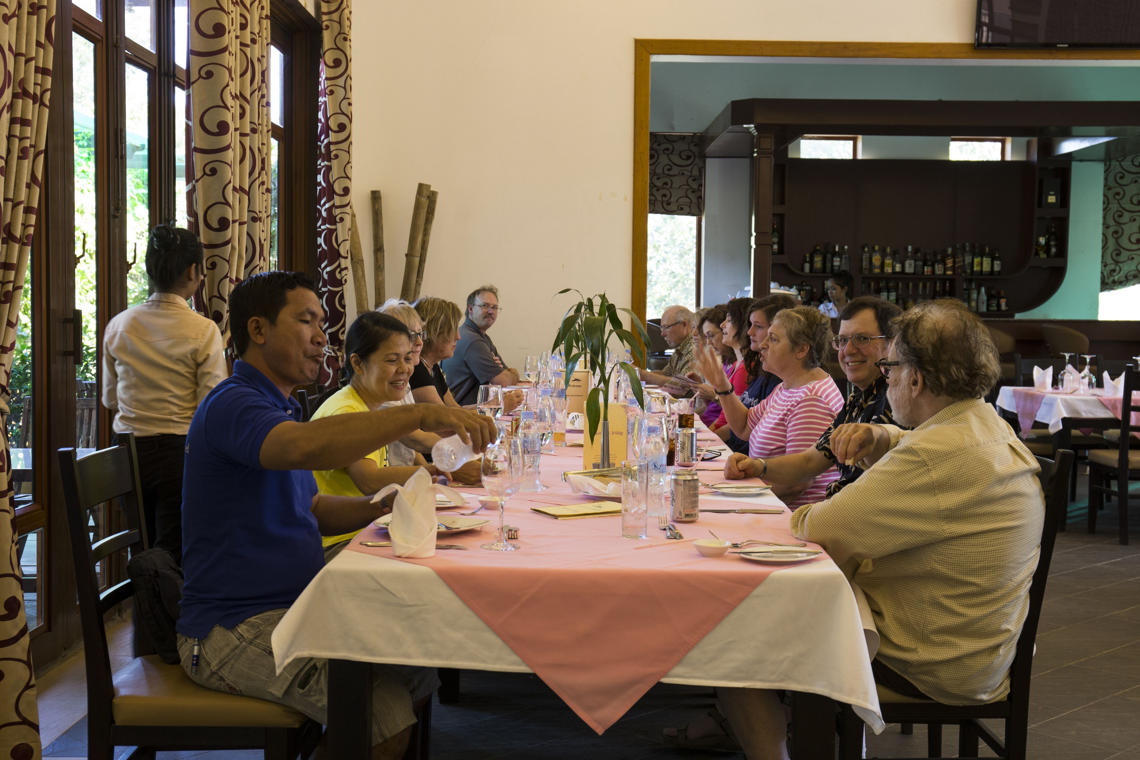 Un grupo de personas cenando en un restaurante, con una mesa dispuesta para la comida.