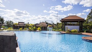A swimming pool with a gazebo and traditional-style buildings in the background. - Samrith Hotel (Baray)
