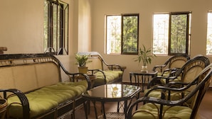 A room with rattan furniture, including a sofa and chairs, a round table, and a potted plant. - Samrith Hotel (Baray)