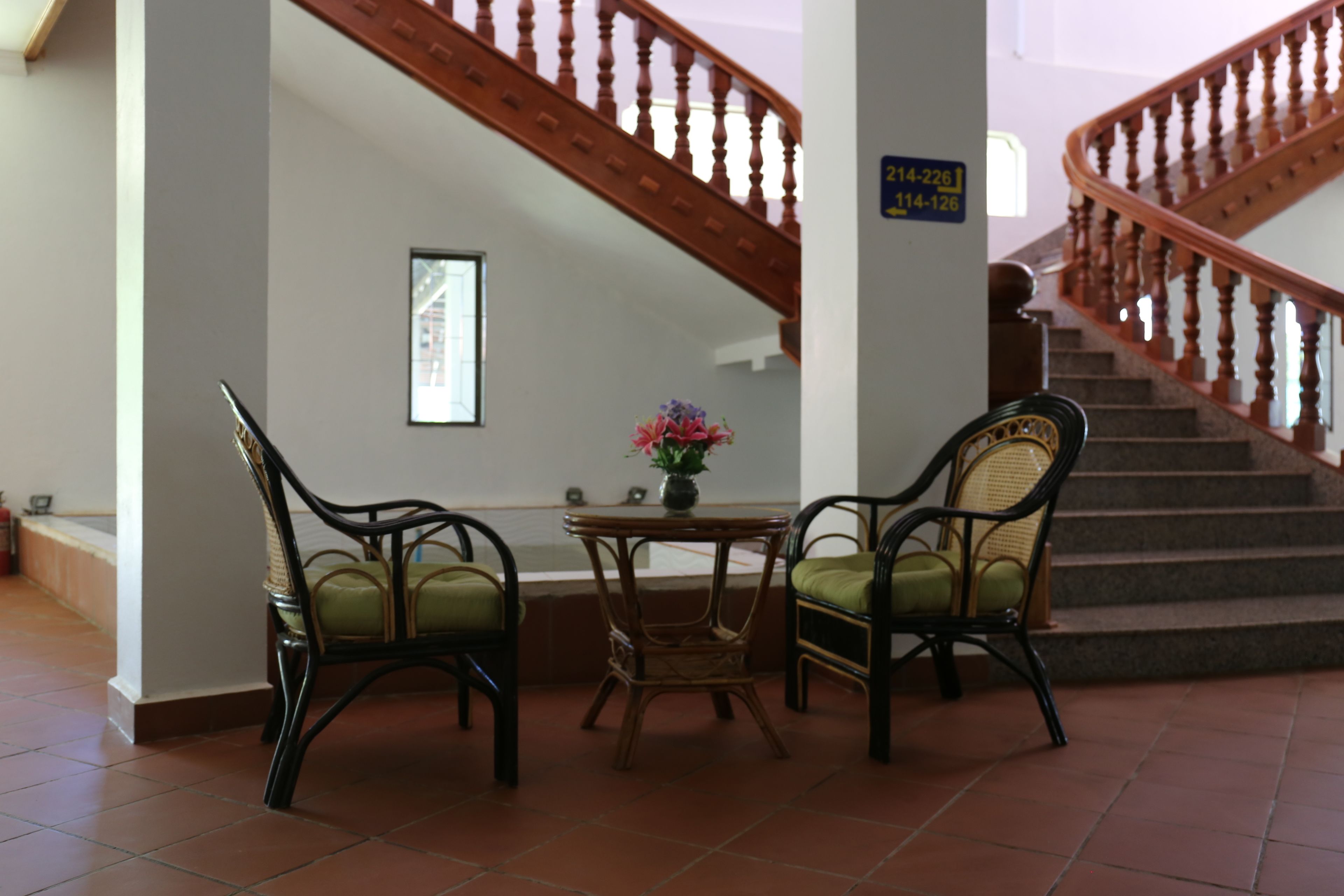 Un escalier avec des rampes en bois, une table avec des chaises et un vase rempli de fleurs.