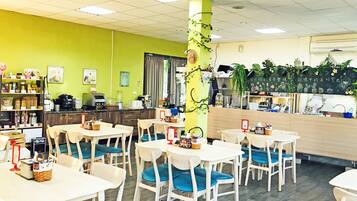 A dining area with tables and chairs, a counter with a coffee machine, and a green wall with decorations.