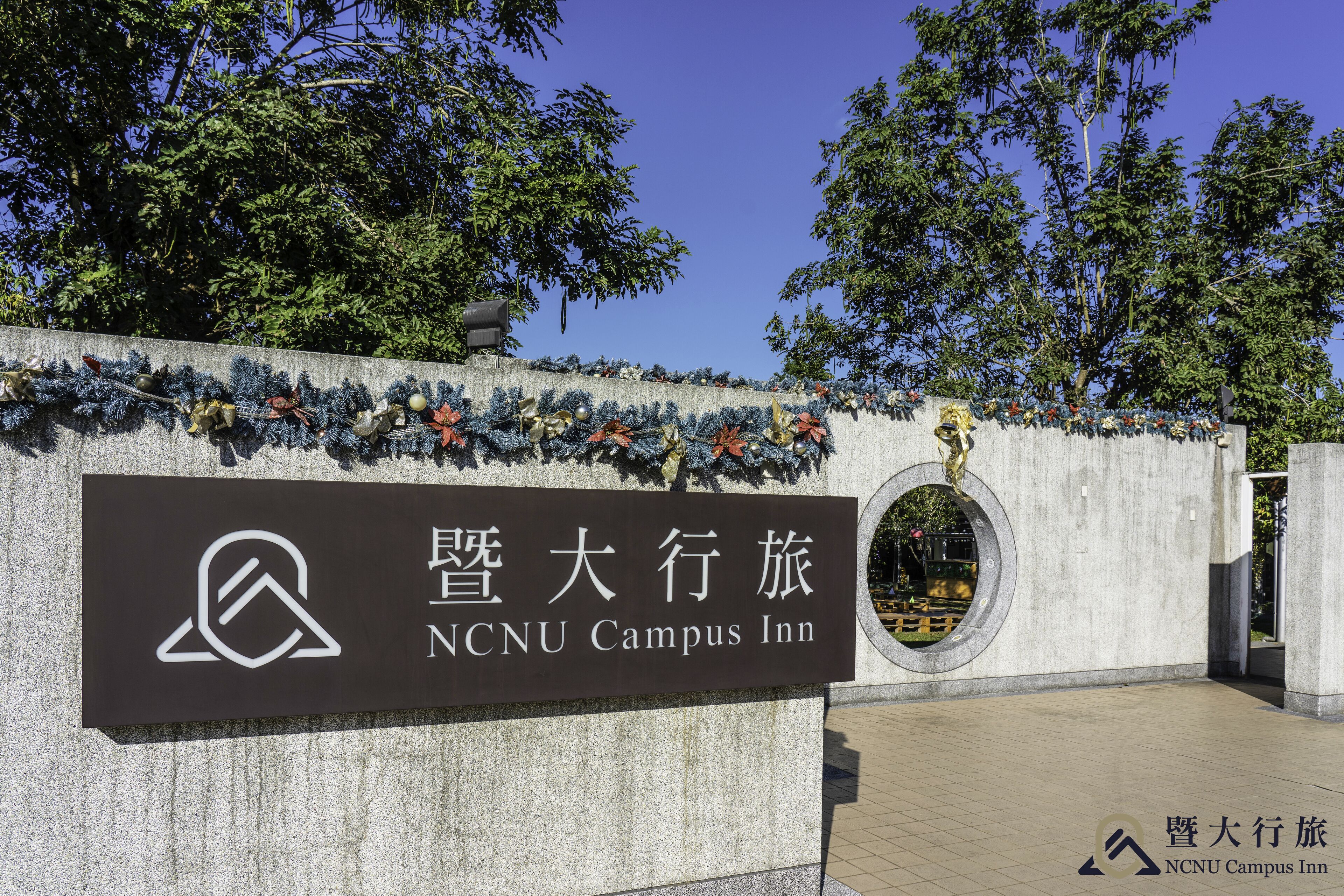 Señal del NCU Campus Inn con un logotipo y caracteres chinos.