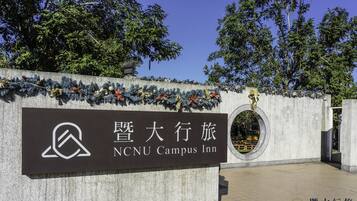 Señal del NCU Campus Inn con un logotipo y caracteres chinos.