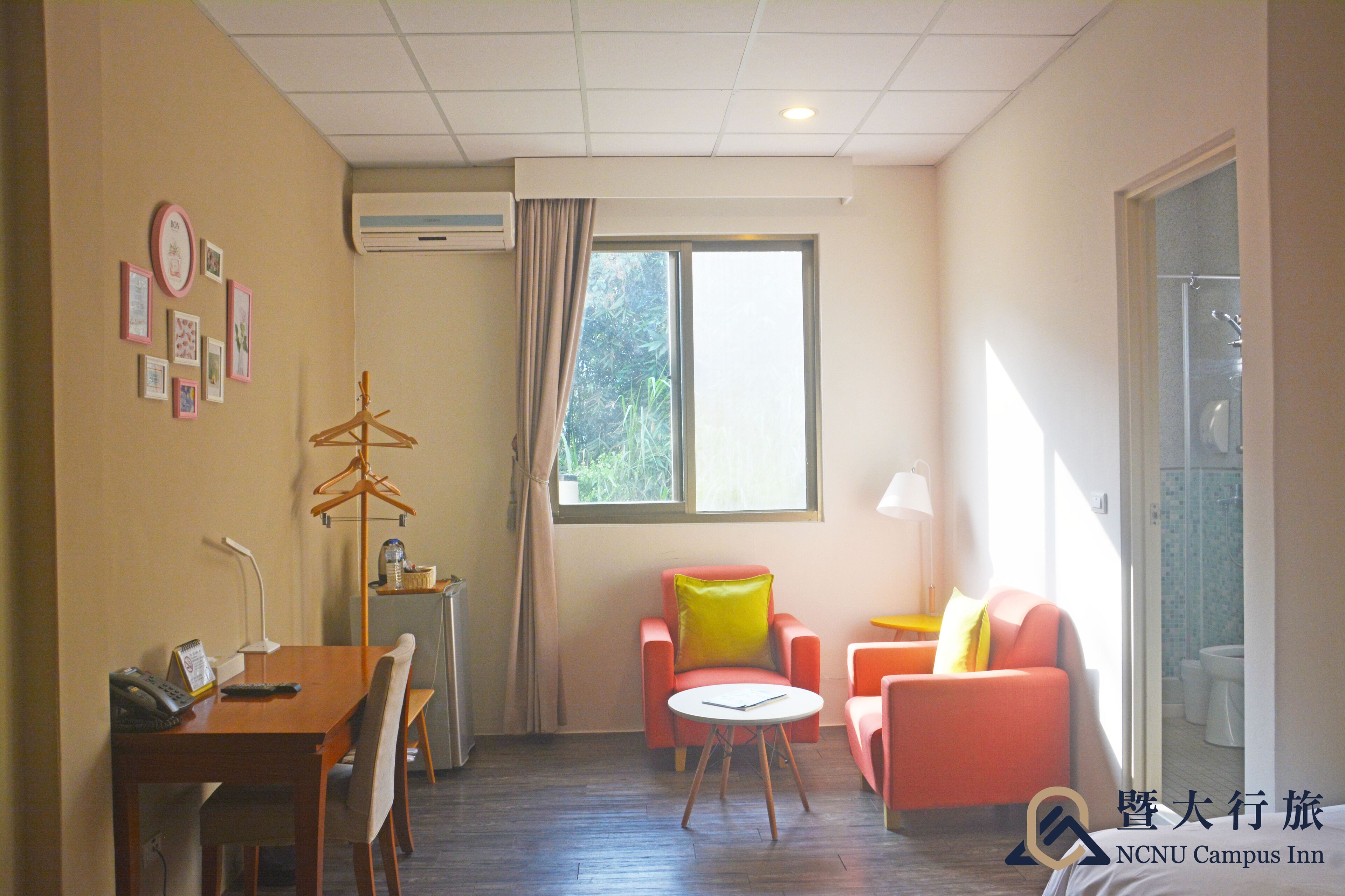 Habitación de hotel con una mesa de comedor, dos sillas, una mesita redonda, un sofá y una ventana con cortinas.