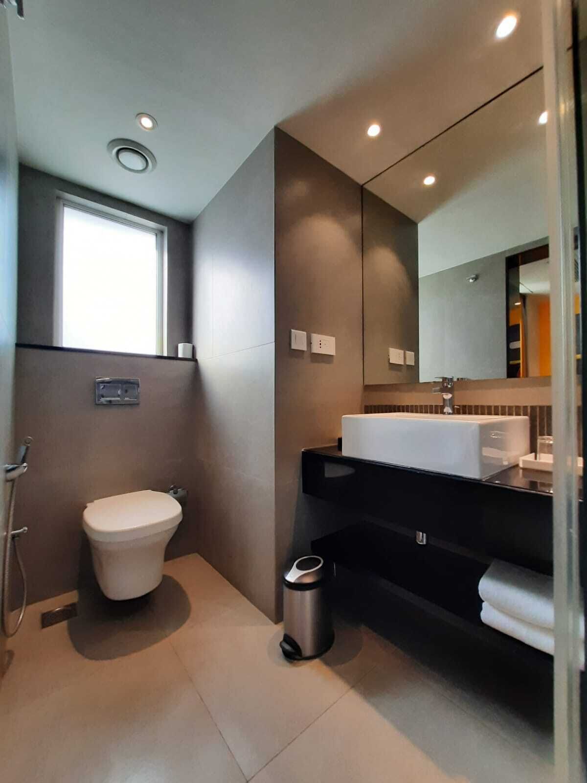 Een moderne badkamer met toilet, wastafel en spiegel.
