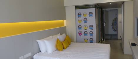 Una habitación de hotel moderna con una cama bien hecha, una mesita de noche y una pared con un adhesivo de un vehículo colorido.