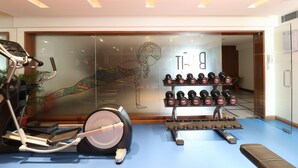 A gym with exercise equipment, including a rowing machine, dumbbells, and a bench.