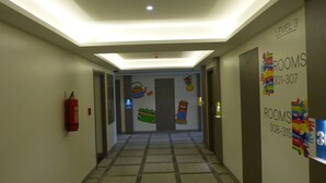 A hallway with a fire extinguisher on the left, a door with a number '303' sign, and a wall with 'LEVEL 3 ROOMS' and contact numbers.
