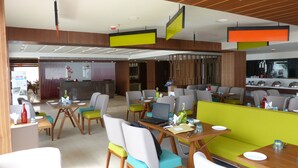 A modern restaurant with wooden paneling, green and white seating, and a bar area.
