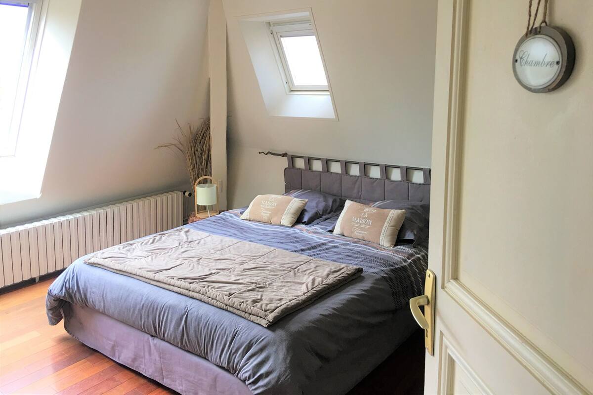 A bedroom with a bed, a radiator, a window, and a skylight.