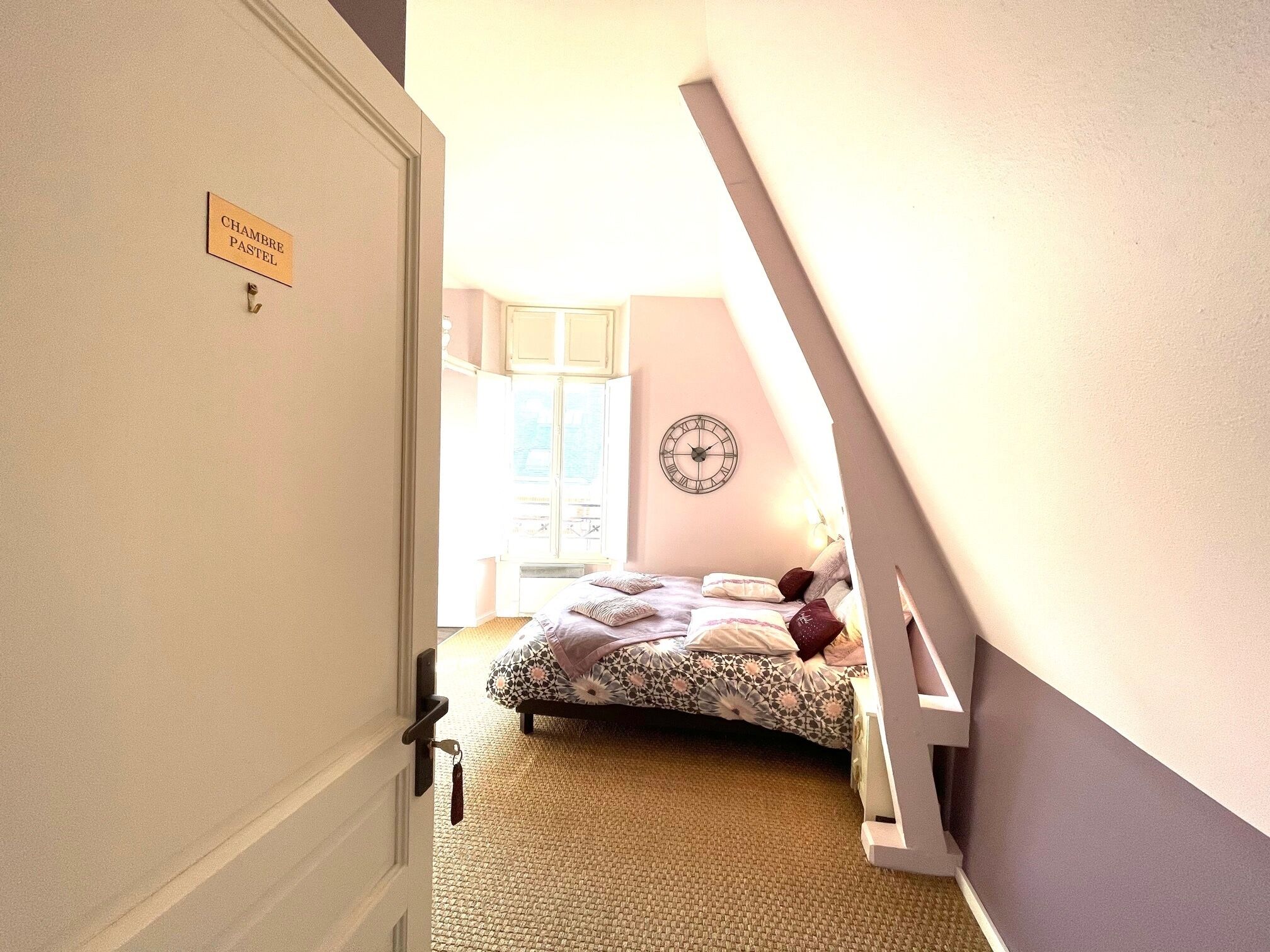 A bedroom with a bed, a clock on the wall, and a door with a sign.