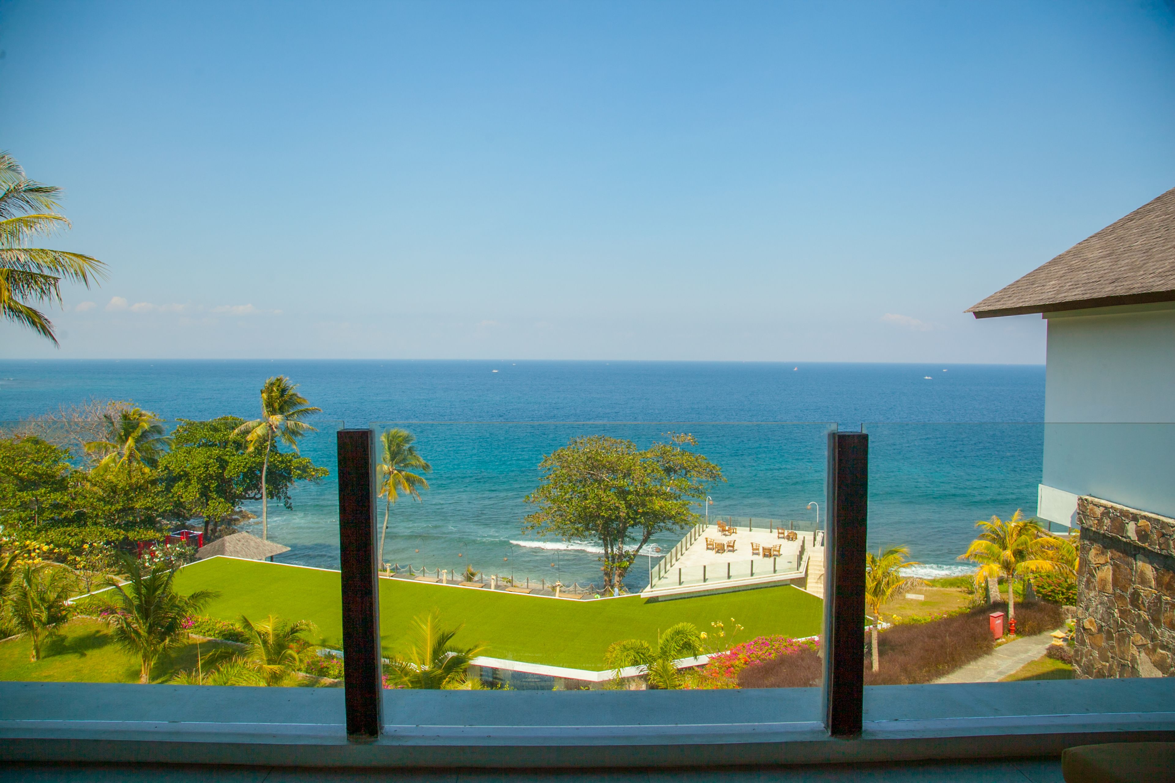Vista de un resort frente a la playa, con piscina, palmeras y el océano.