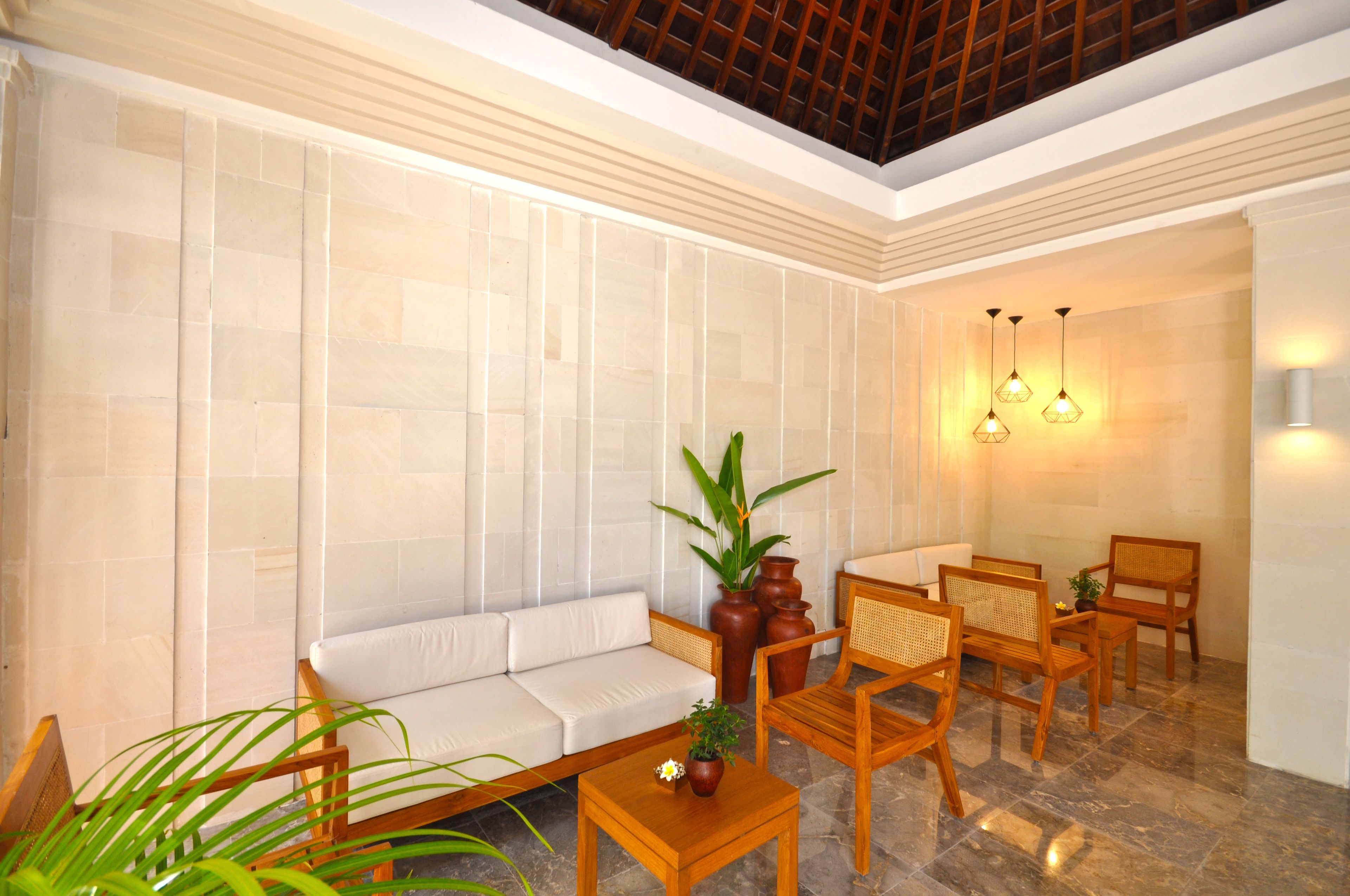 A modern interior with a sofa, wooden chairs, a small table, and decorative plants.