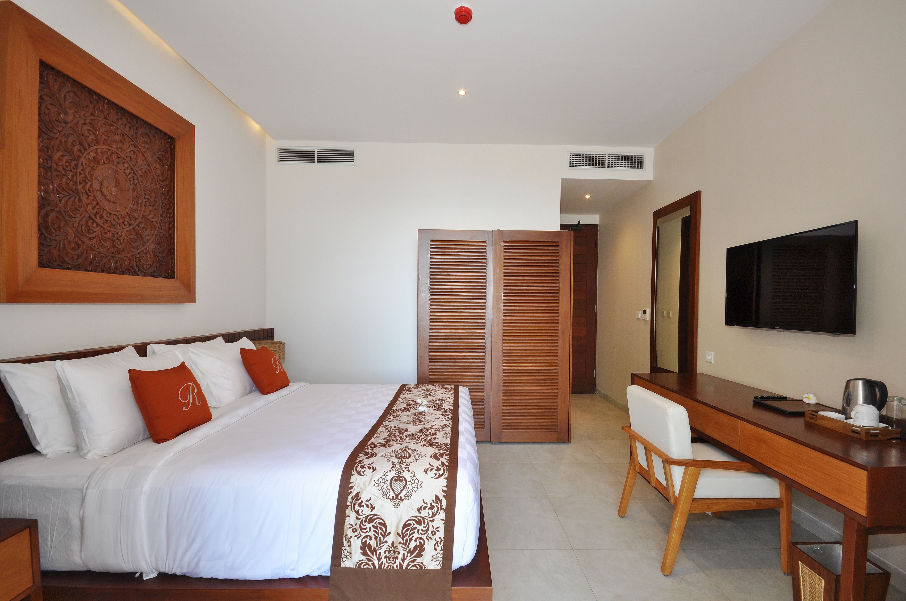 Una habitación de hotel con cama, escritorio, silla, televisor y armario.