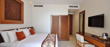 Una habitación de hotel con cama, escritorio, silla, televisor y armario.