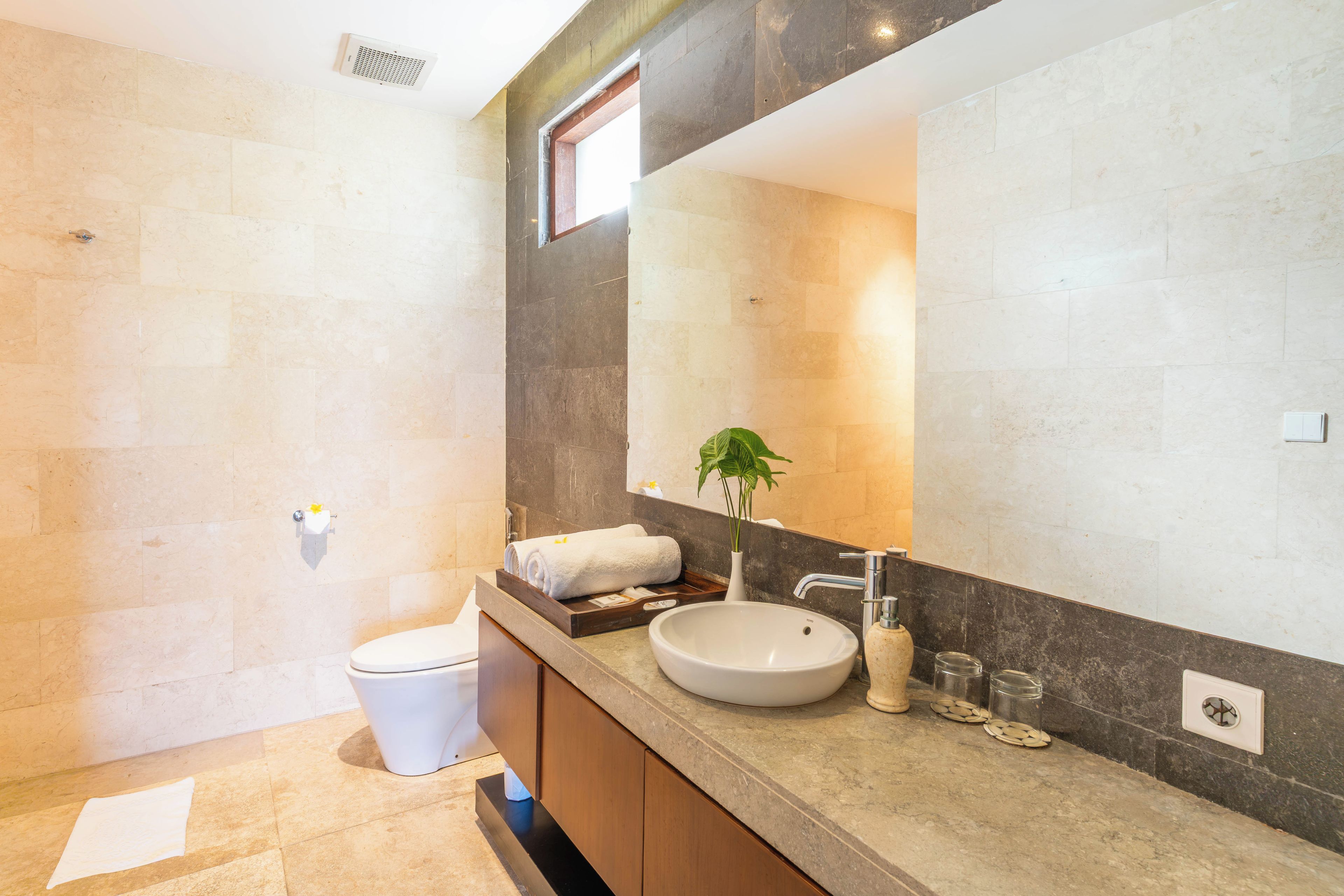 Een moderne badkamer met een grote spiegel, een wastafel en een toilet.
