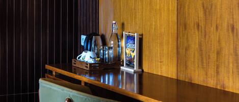 A modern office desk with a laptop, a coffee machine, and a poster.