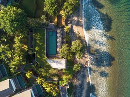 Vista aérea de un resort con piscina, zona de descanso y acceso a la playa.