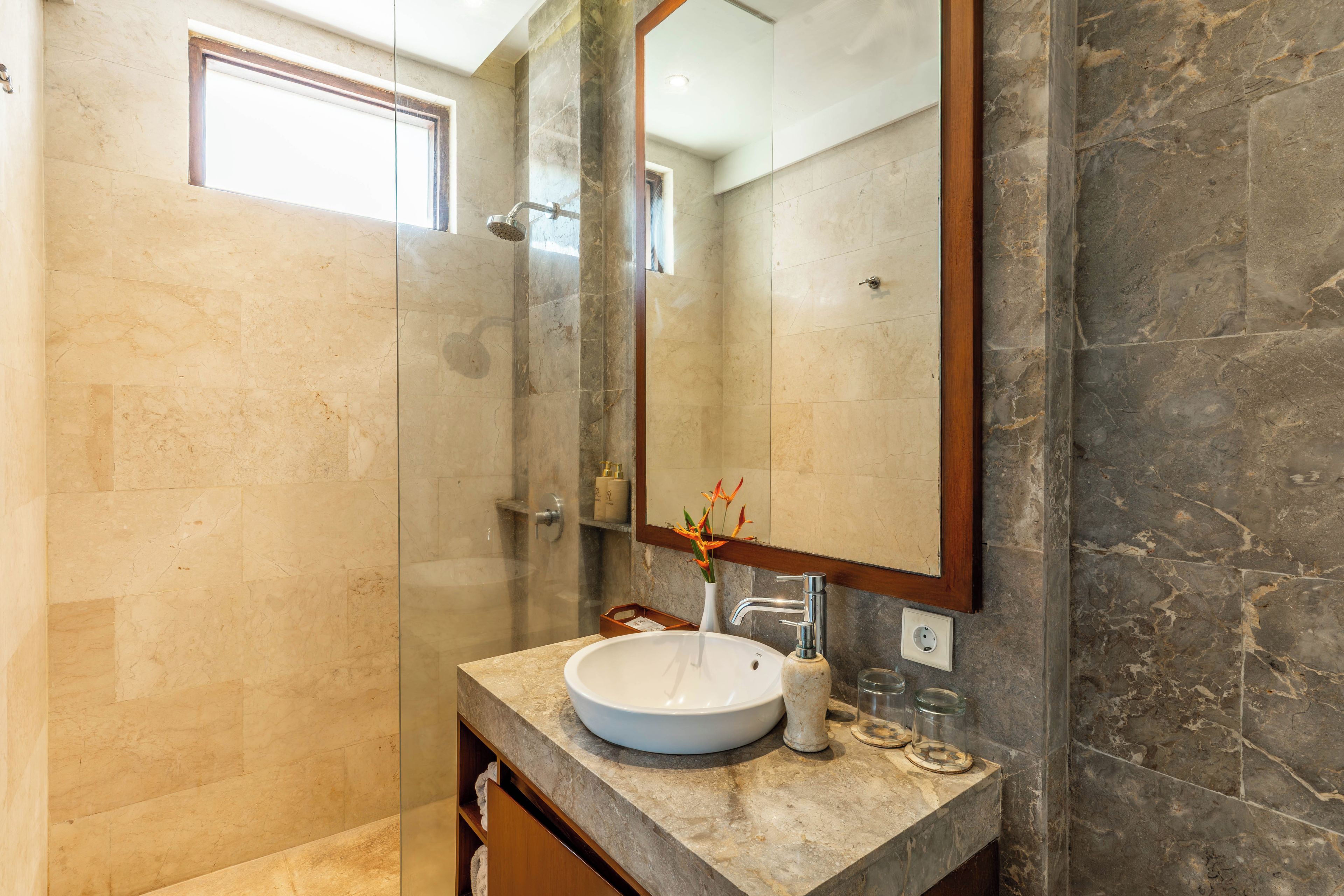 Une salle de bain avec un grand miroir, un lavabo et un espace douche.