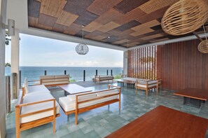 A modern room with a view of the sea, featuring a wooden ceiling, a woven ceiling light, and a wooden floor. - Rajavilla Lombok Resort (Senggigi)